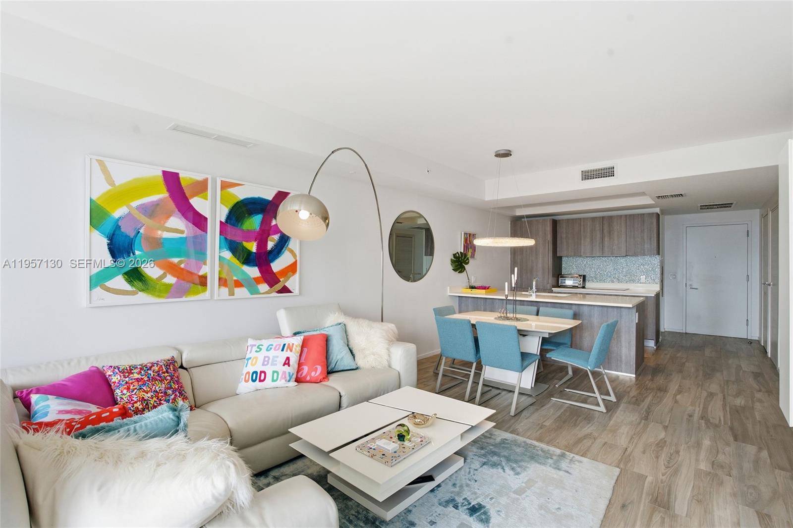 A modern living and dining area features a white sofa, colorful art, and kitchen island — 801 S Miami Ave # 4202, Miami FL 33130, MIAMI, FL