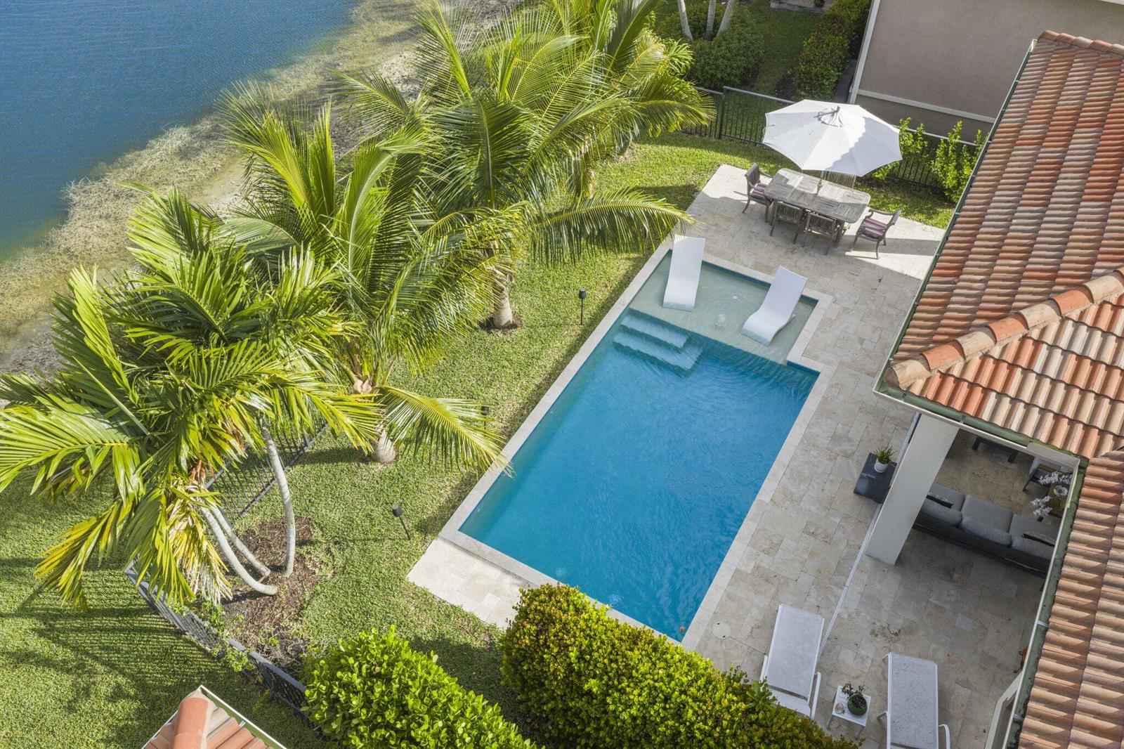 An aerial view of a backyard featuring a swimming pool, patio, and palm trees — 9031 Leon Circle W, Parkland FL 33076, PARKLAND, FL