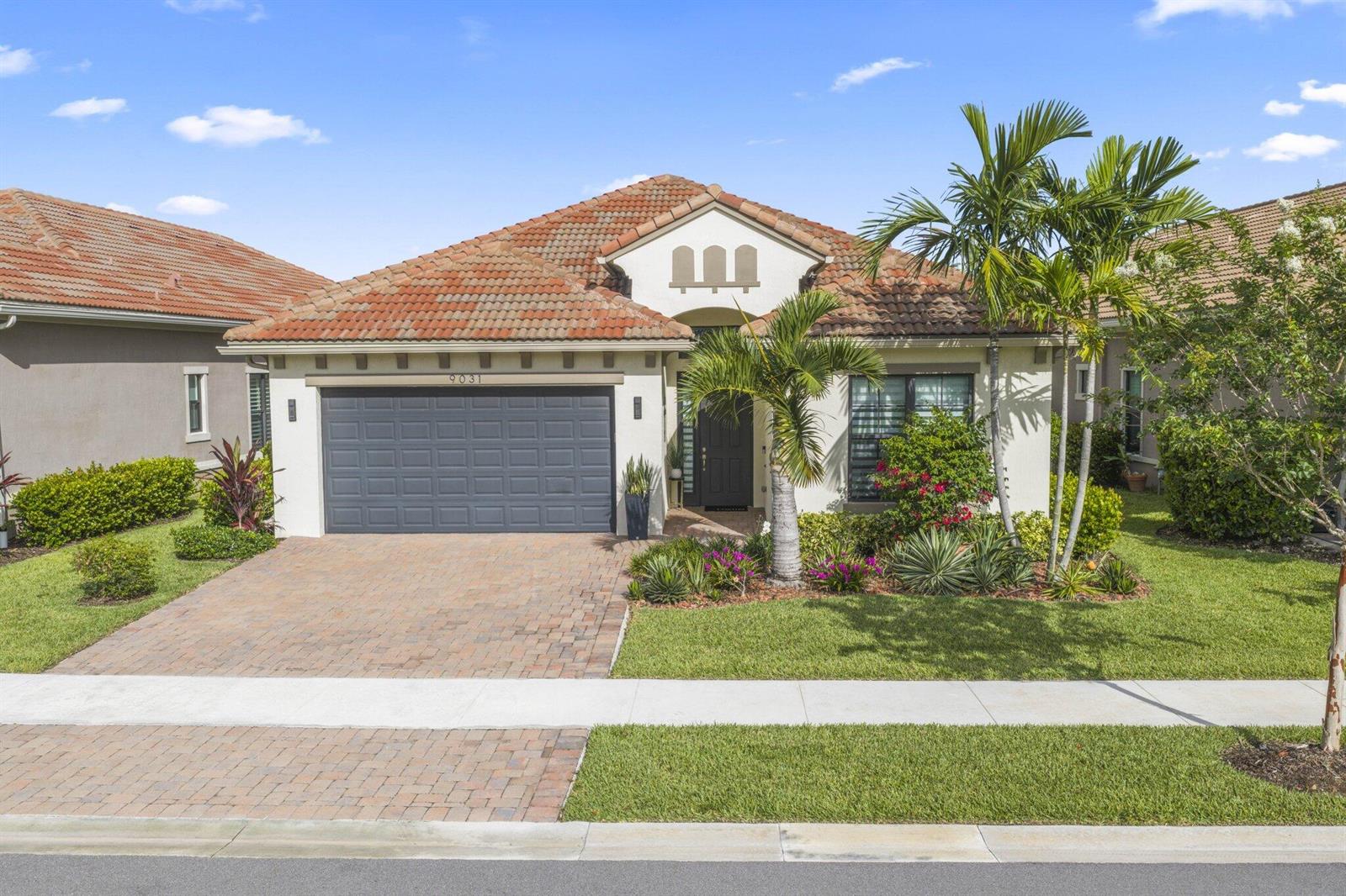 A single-story house with a tiled roof, a gray garage door, and a landscaped front yard — 9031 Leon Circle W, Parkland FL 33076, PARKLAND, FL