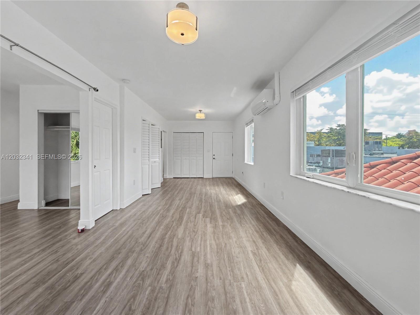 A bright, empty room features light wood-look flooring, white walls, and a large window — 350 Minorca Ave # 2, Coral Gables FL 33134, CORAL GABLES, FL