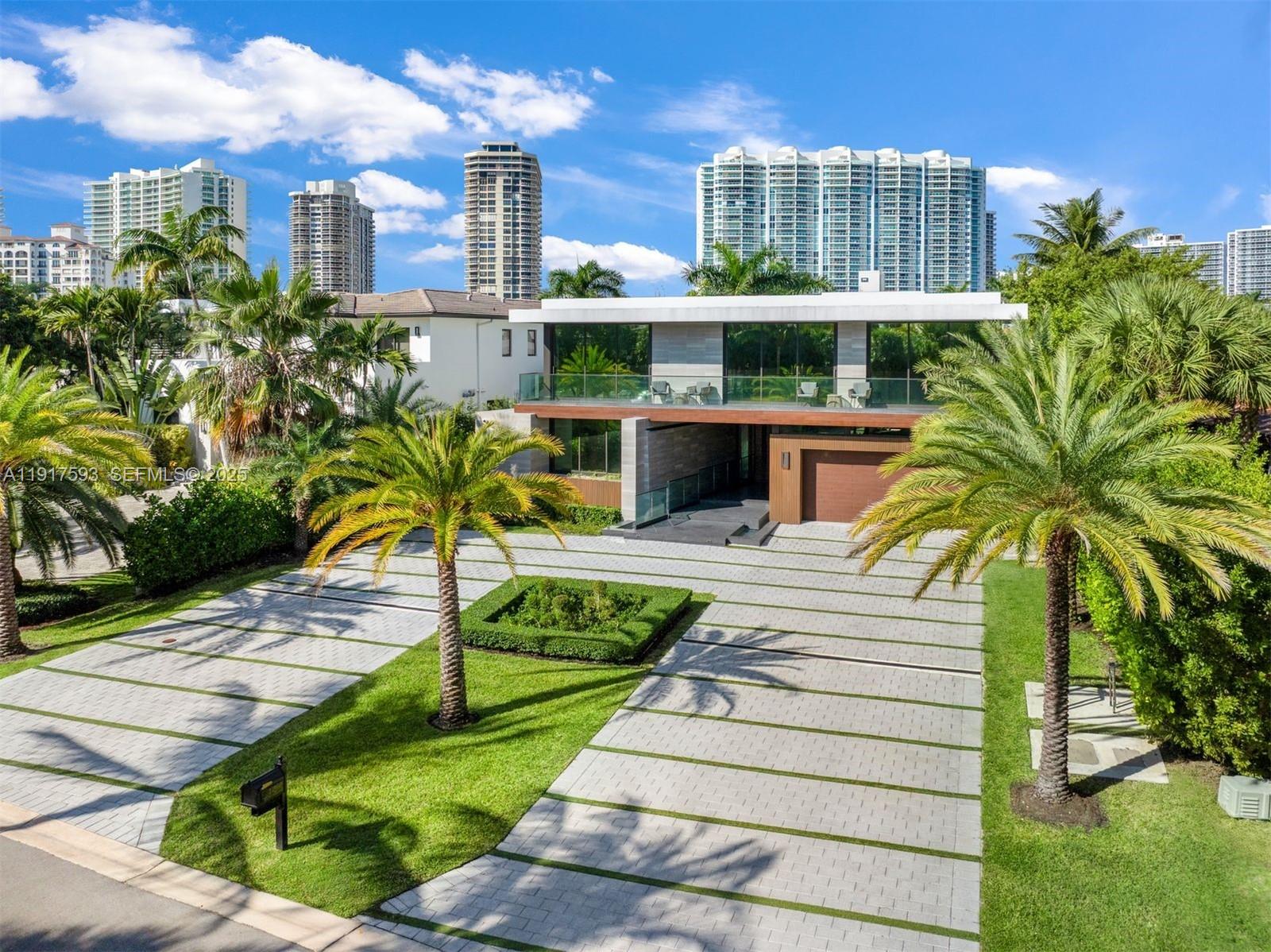 A modern two-story house with a paved driveway, palm trees, and a glass balcony — 342 S Parkway, Golden Beach FL 33160, GOLDEN BEACH, FL