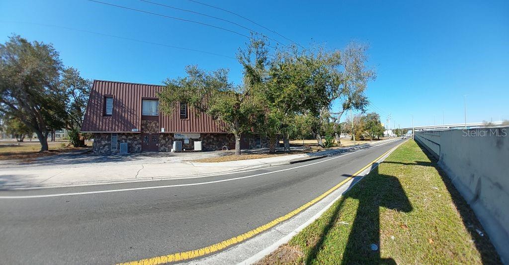 A two-story commercial building with a brown metal roof and stone facade sits beside a road — 11400 US HIGHWAY 19 N, CLEARWATER, FL