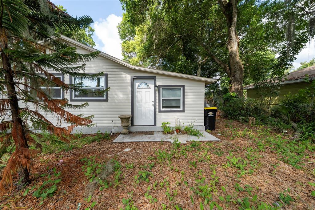 A white-sided house exterior features a front door, two windows, and a concrete entryway — 310 CORDOVA ROAD, AUBURNDALE, FL