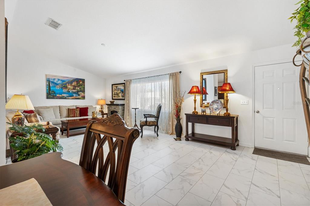 A living room with white tile floors, a sofa, a console table, and a fireplace — 9498 SE 174TH LOOP, SUMMERFIELD, FL