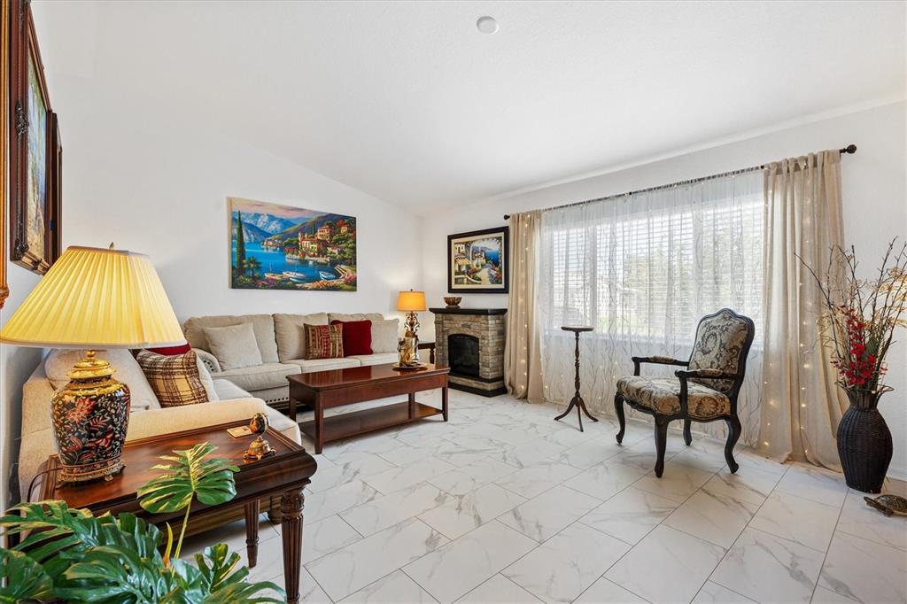 A living room features white marble tile flooring, a stone fireplace, and a beige sofa — 9498 SE 174TH LOOP, SUMMERFIELD, FL