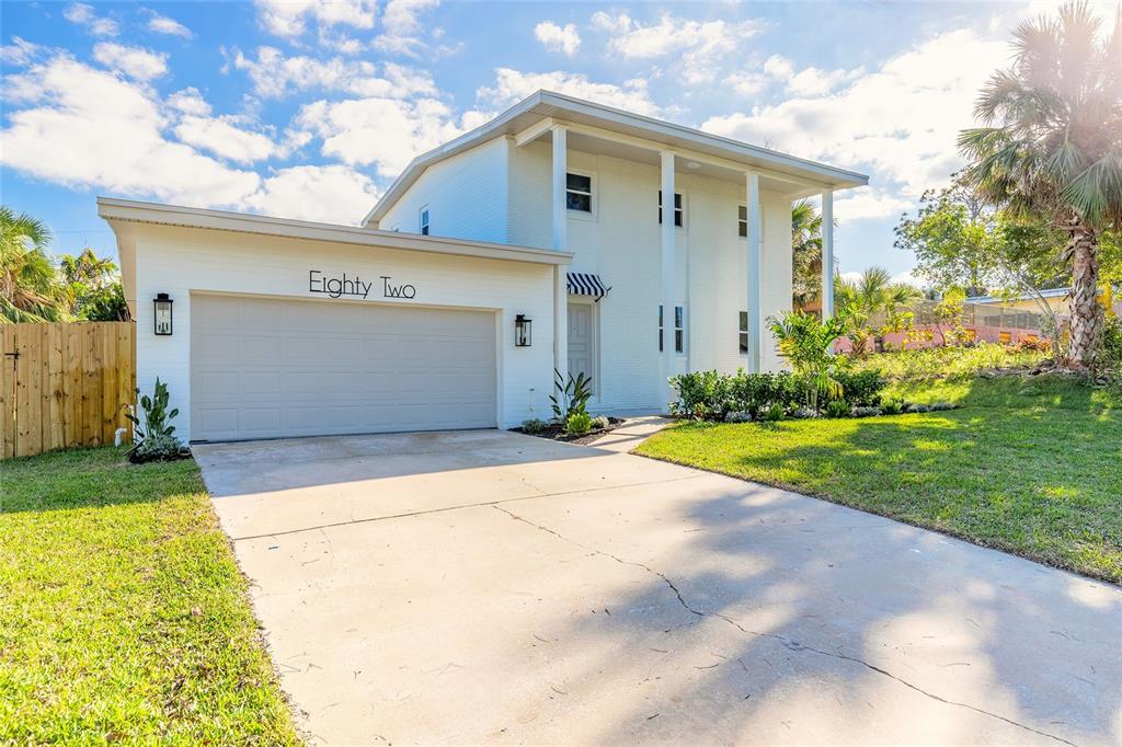 A two-story white house with a garage and a concrete driveway under a blue sky — 82 RAY MAR DRIVE, ORMOND BEACH, FL