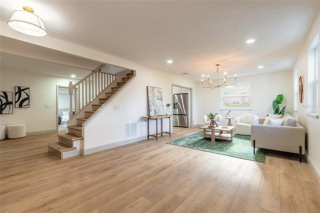 A living room features light wood flooring, a staircase with a railing, and a sofa area — 82 RAY MAR DRIVE, ORMOND BEACH, FL