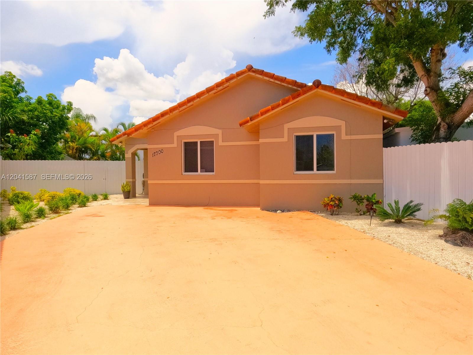 A single-story house with a tan stucco exterior, tile roof, and a large concrete driveway — 17700 SW 145th Ave, Miami FL 33177, MIAMI, FL
