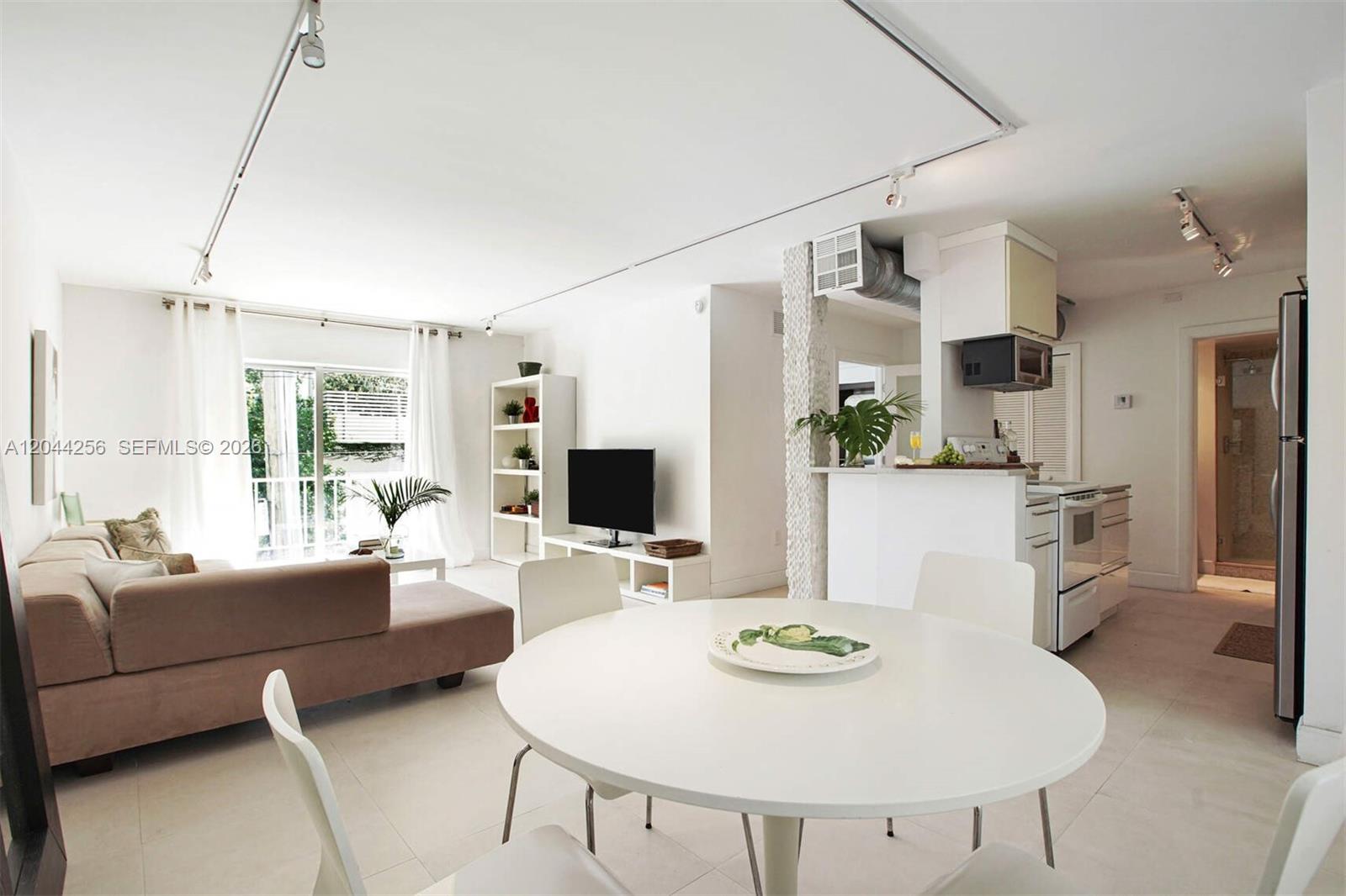 A bright open-concept living and dining area features white walls, tile floors, and modern furniture — 201 Jefferson Ave # 2E, Miami Beach FL 33139, MIAMI BEACH, FL