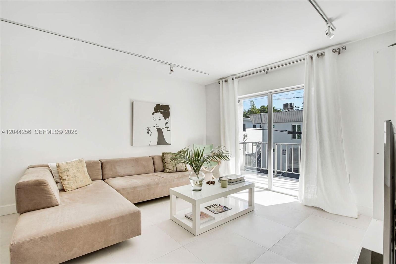 A living room features a beige sectional sofa, a white coffee table, and a balcony — 201 Jefferson Ave # 2E, Miami Beach FL 33139, MIAMI BEACH, FL