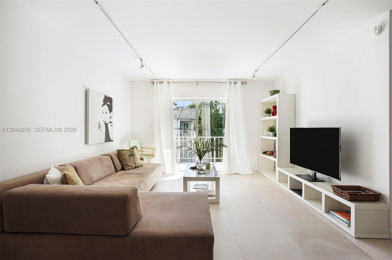 A living room features a brown sectional sofa, a white media console, and a balcony — 201 Jefferson Ave # 2E, Miami Beach FL 33139, MIAMI BEACH, FL