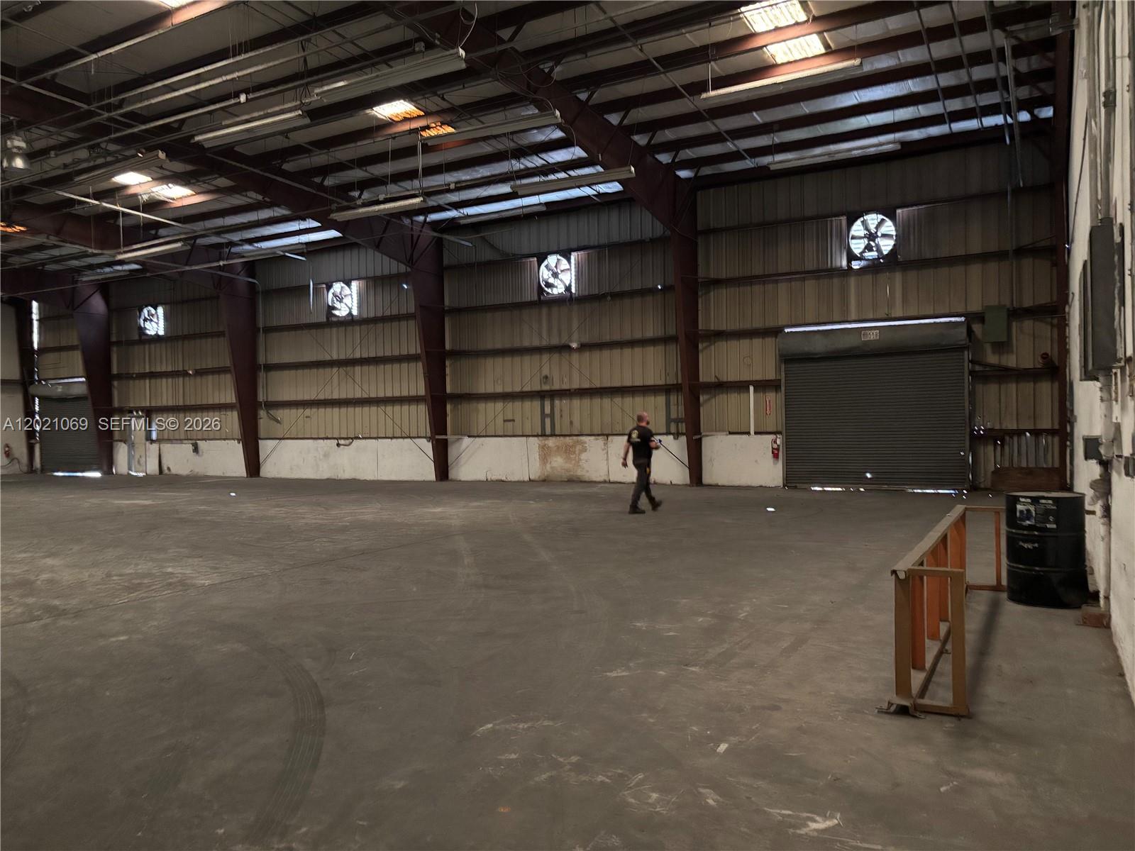 A large, open warehouse interior features a concrete floor, metal walls, and industrial exhaust fans — 50 NE 179th St., Miami Gardens FL 33162, MIAMI GARDENS, FL