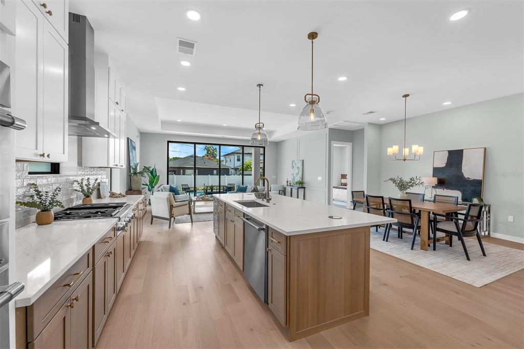 A modern kitchen features a large island, white countertops, and light wood cabinetry — 9 E STEELE STREET, ORLANDO, FL