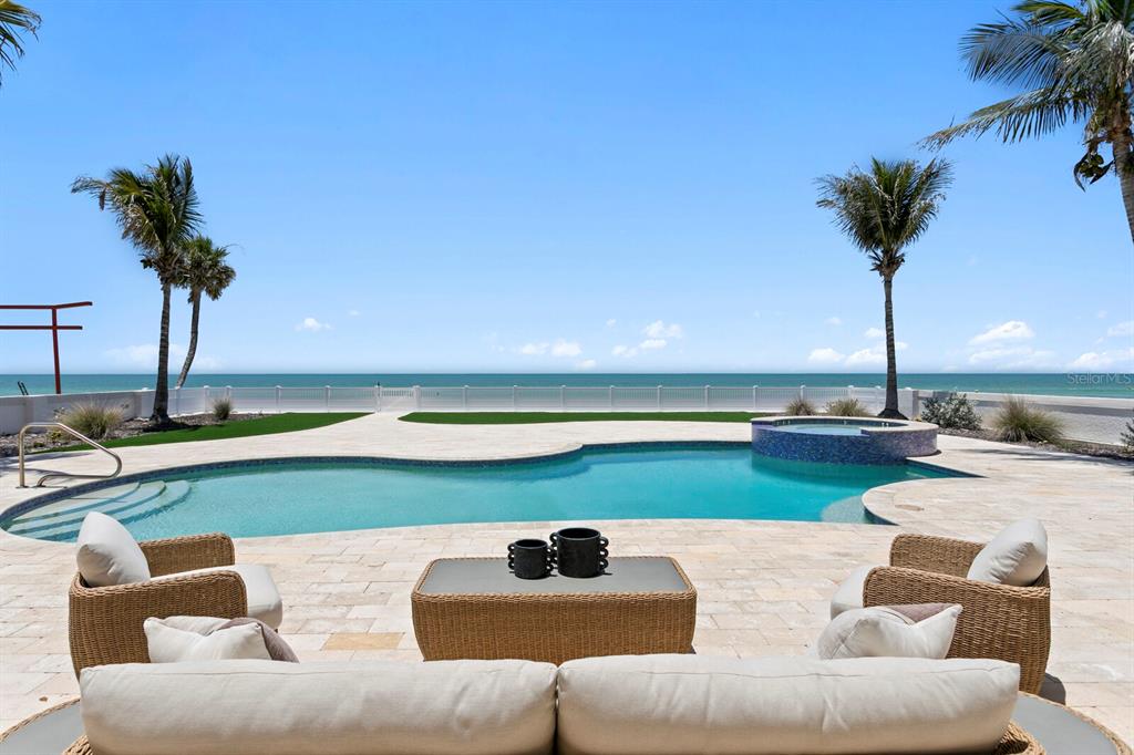 A swimming pool and spa overlook the ocean from a paved patio with outdoor furniture — 15912 GULF BOULEVARD, REDINGTON BEACH, FL