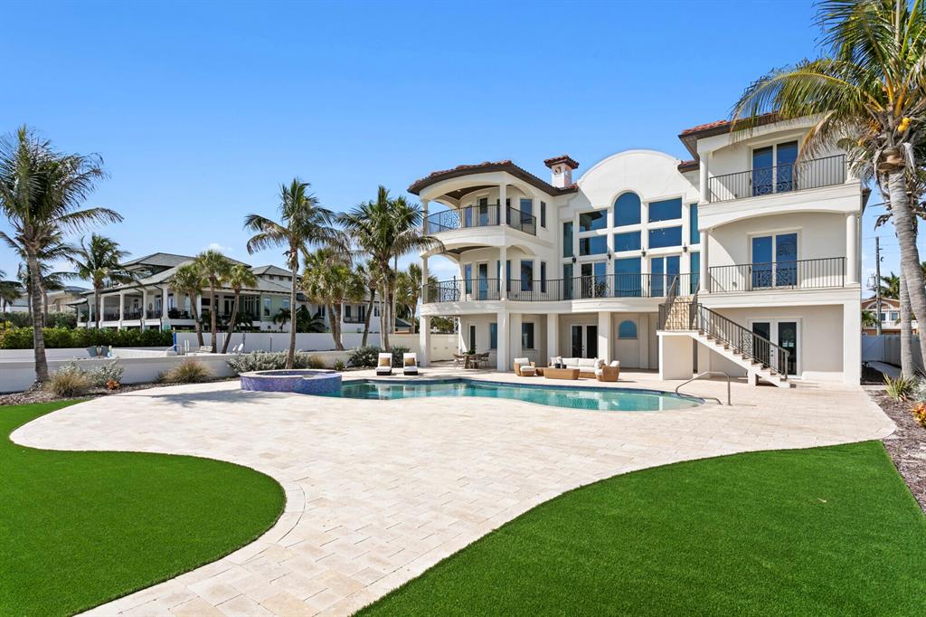 A multi-story house with a pool, patio, and palm trees under a clear blue sky — 15912 GULF BOULEVARD, REDINGTON BEACH, FL