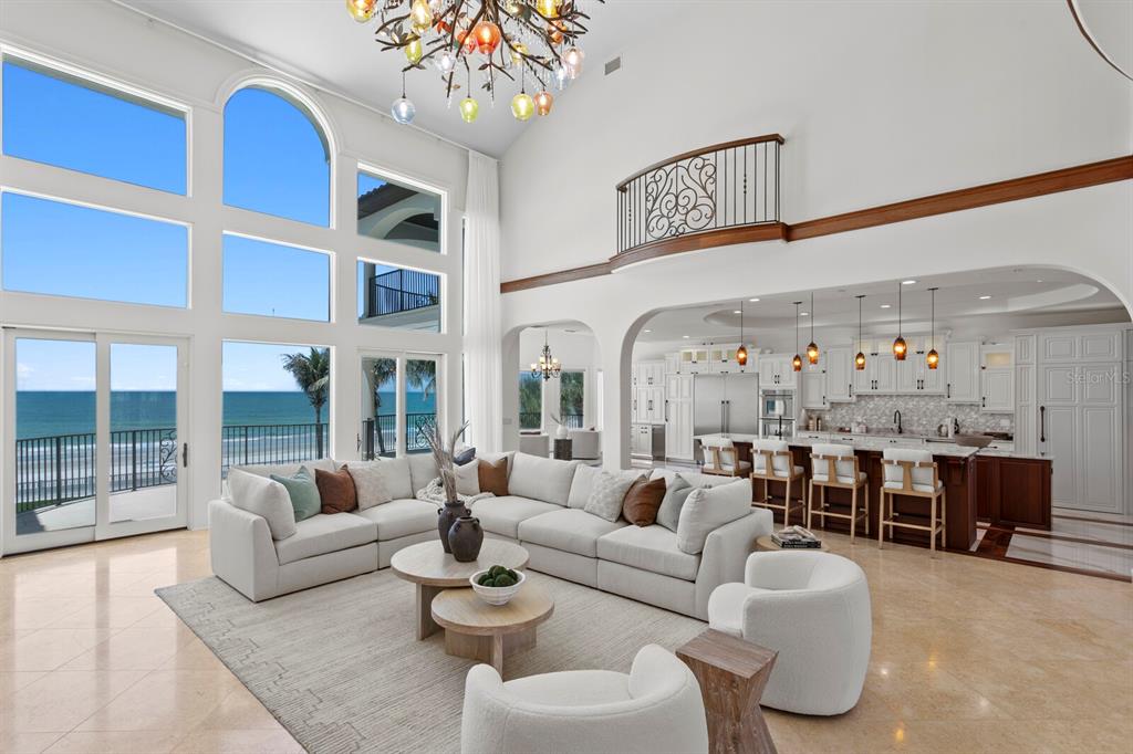 A spacious living room with high ceilings, a large sectional, and ocean views through windows — 15912 GULF BOULEVARD, REDINGTON BEACH, FL