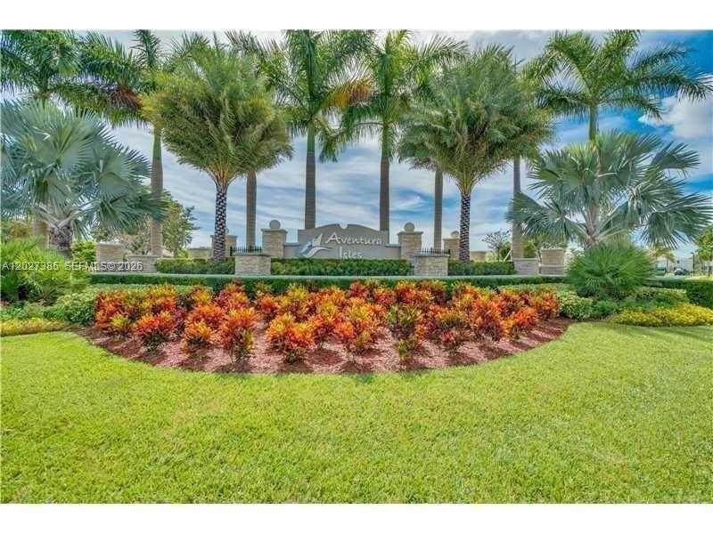 A stone monument sign for Aventura Isles sits behind a landscaped garden with palm trees — 311 NE 194th Ln # 311, Miami FL 33179, MIAMI, FL