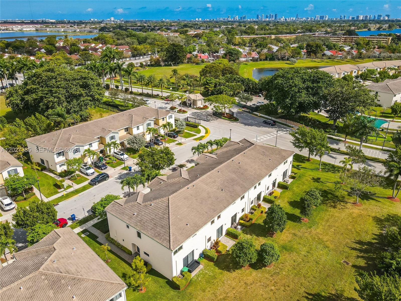 An aerial view shows multi-story residential townhomes surrounded by green lawns and paved streets — 311 NE 194th Ln # 311, Miami FL 33179, MIAMI, FL