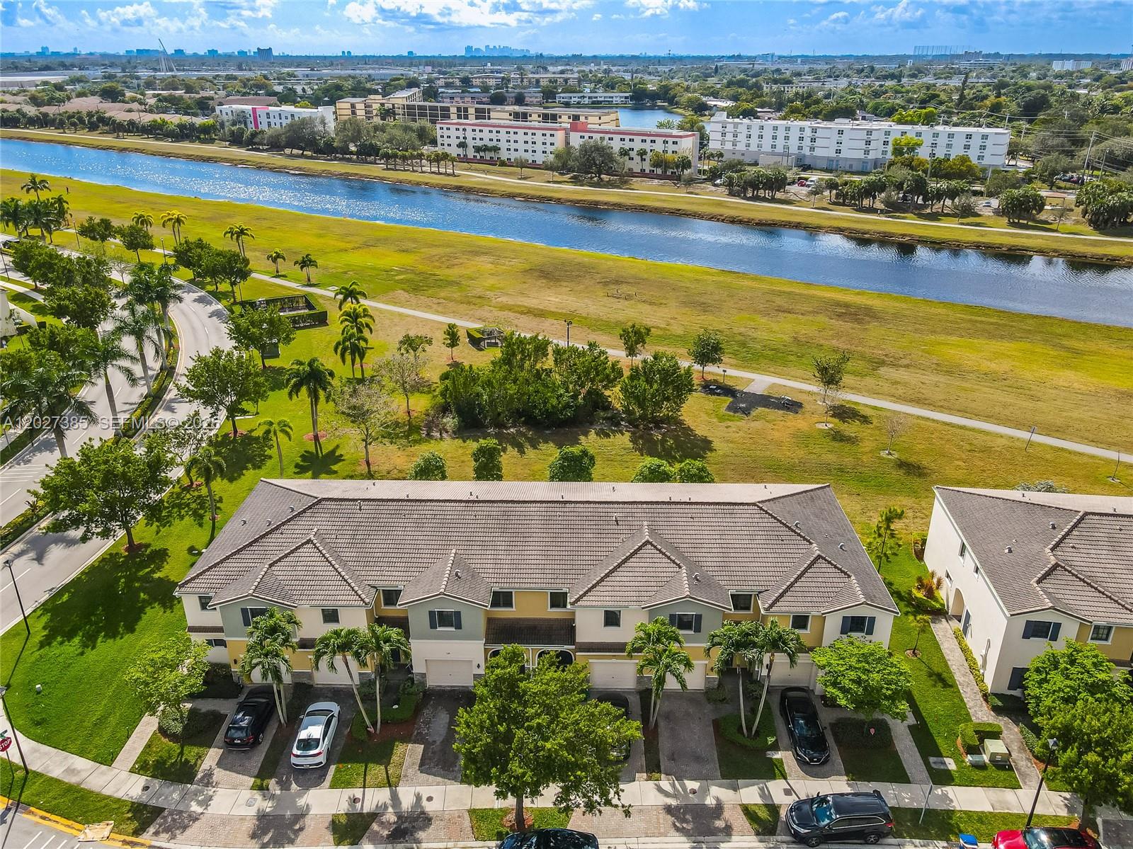 An aerial view shows a multi-unit townhouse building with a canal and park behind it — 311 NE 194th Ln # 311, Miami FL 33179, MIAMI, FL