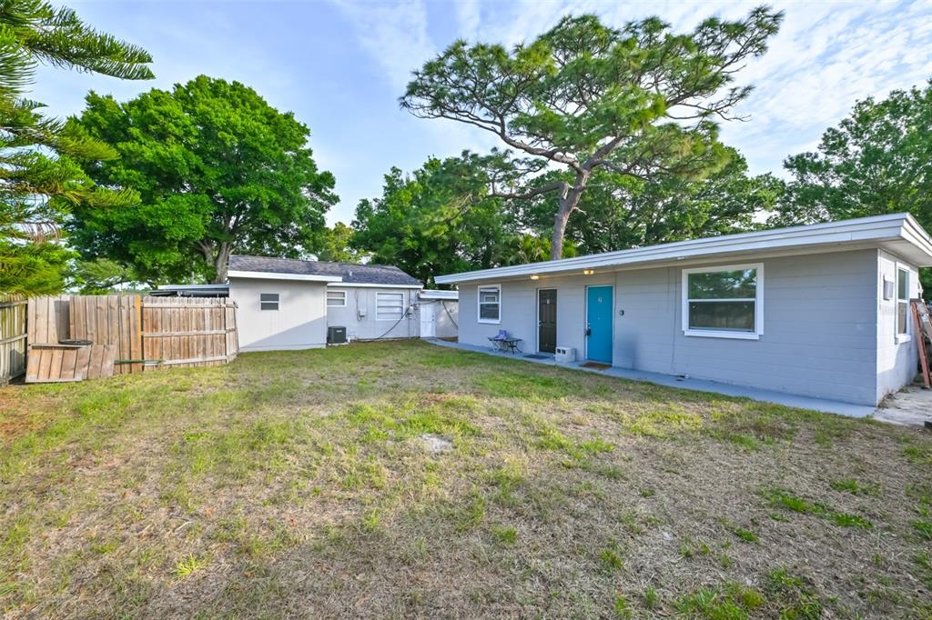 A single-story gray duplex building with two entry doors sits behind a grassy yard — 1956 MCMULLEN ROAD UNIT 2, LARGO, FL