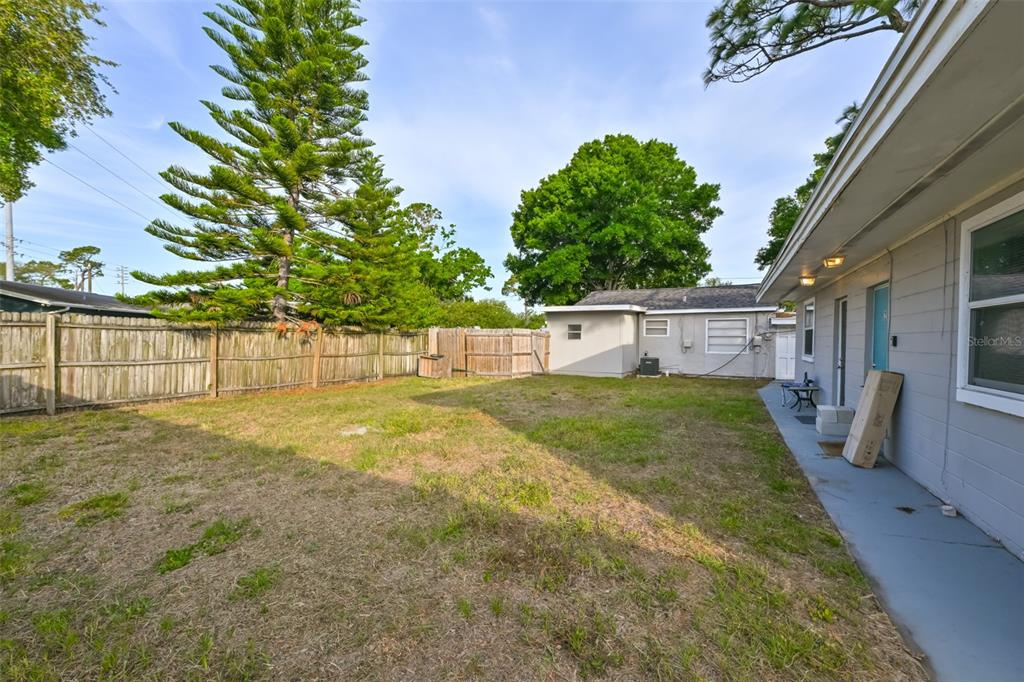 A fenced backyard features a grassy lawn, a detached garage, and the side of a house — 1956 MCMULLEN ROAD UNIT 2, LARGO, FL