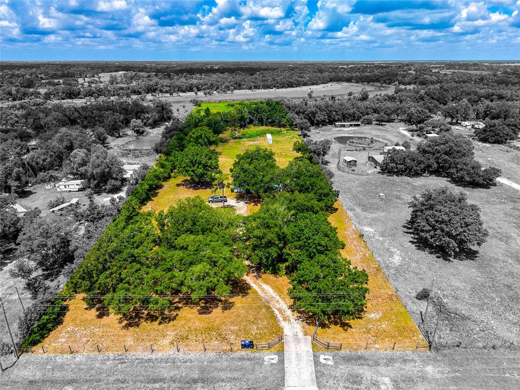 An aerial view shows a rectangular, tree-lined property with a gravel driveway and small structures — 14110 SUGAR BOWL ROAD, MYAKKA CITY, FL