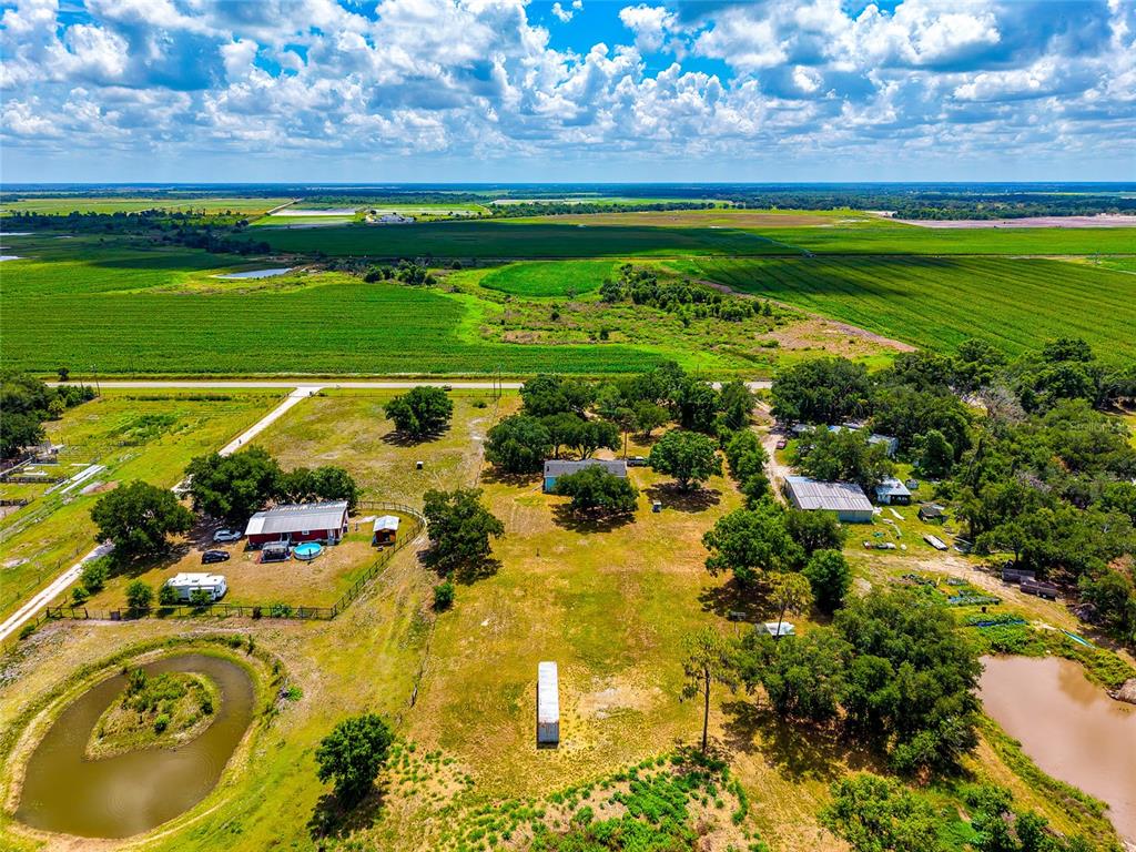 An aerial view shows a rural property with multiple buildings, trees, and a small pond — 14110 SUGAR BOWL ROAD, MYAKKA CITY, FL