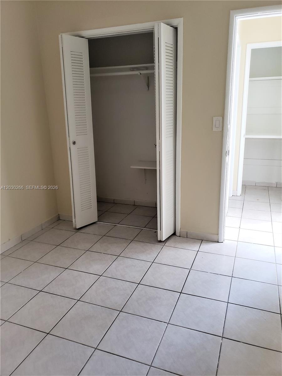 A room with light-colored tile flooring, a white louvered closet, and an adjacent doorway — 1821 SW 7th St # 7, Miami FL 33135, MIAMI, FL