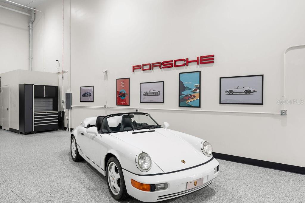 A white Porsche convertible is parked inside a garage with white walls and framed artwork — 5431 COMMUNICATIONS PARKWAY UNIT 28, LAKEWOOD RANCH, FL