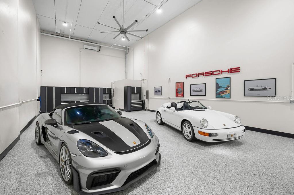 A spacious garage with white walls, epoxy flooring, and two parked Porsche sports cars — 5431 COMMUNICATIONS PARKWAY UNIT 28, LAKEWOOD RANCH, FL