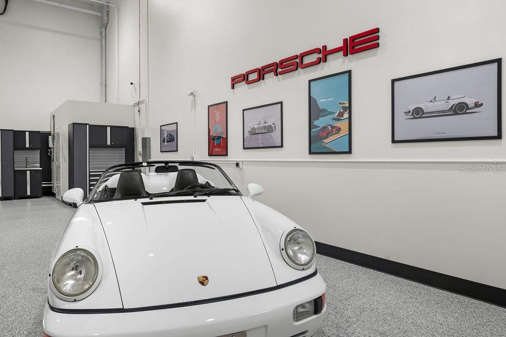 A white Porsche convertible is parked inside a garage with white walls and artwork — 5431 COMMUNICATIONS PARKWAY UNIT 28, LAKEWOOD RANCH, FL