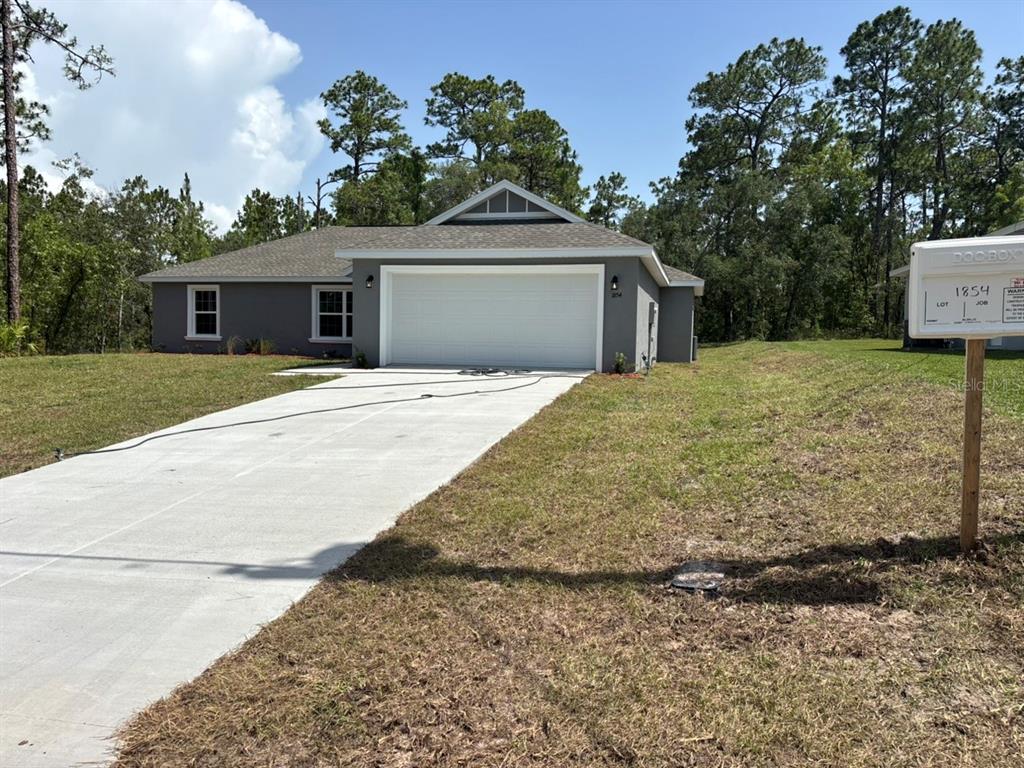 A newly constructed gray single-story house with a white garage door and a concrete driveway — 1854 W CARY DRIVE, DUNNELLON, FL