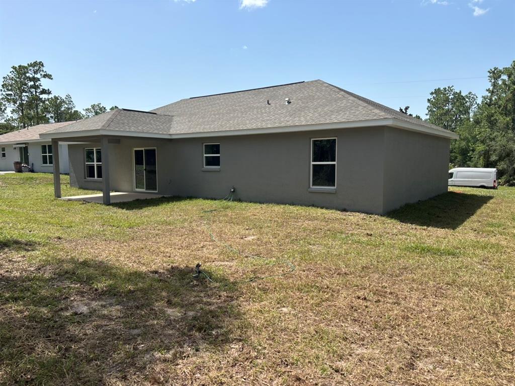 The exterior rear view of a single-story house features a covered patio and a grassy yard — 1854 W CARY DRIVE, DUNNELLON, FL