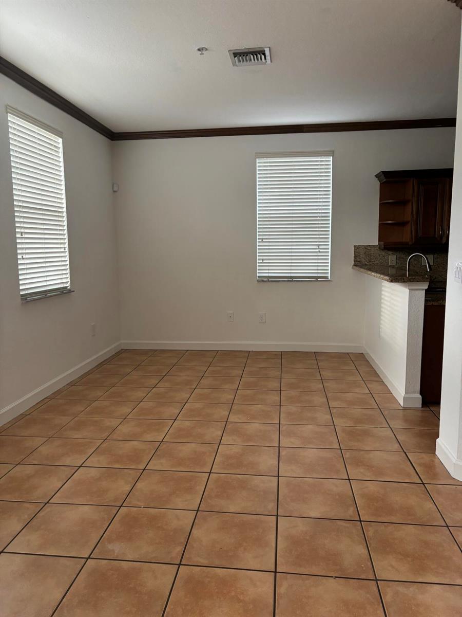 An empty dining area features tan tile flooring, two windows with blinds, and crown molding — 4311 SW 160th Avenue # 210, Miramar FL 33027, MIRAMAR, FL