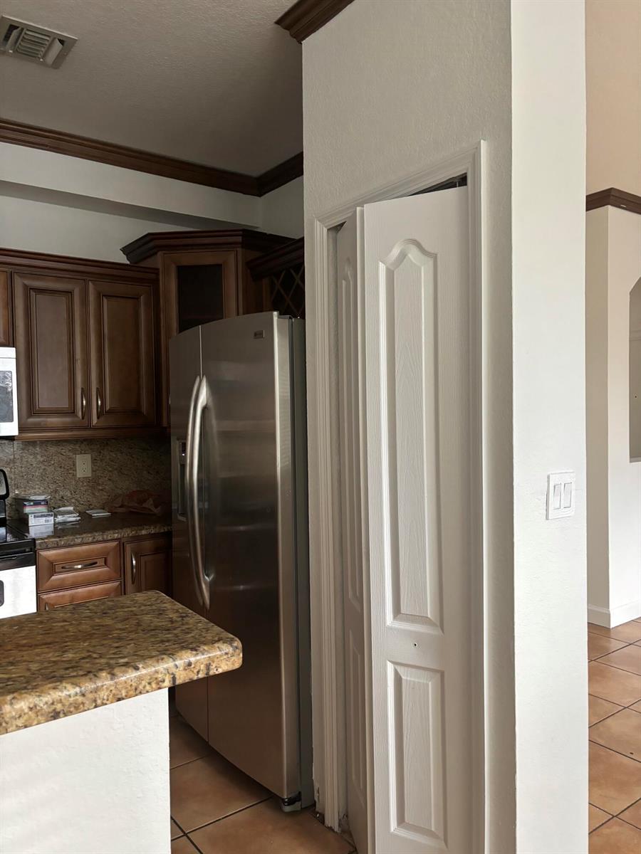 A kitchen features dark wood cabinets, stainless steel appliances, granite countertops, and a pantry door — 4311 SW 160th Avenue # 210, Miramar FL 33027, MIRAMAR, FL