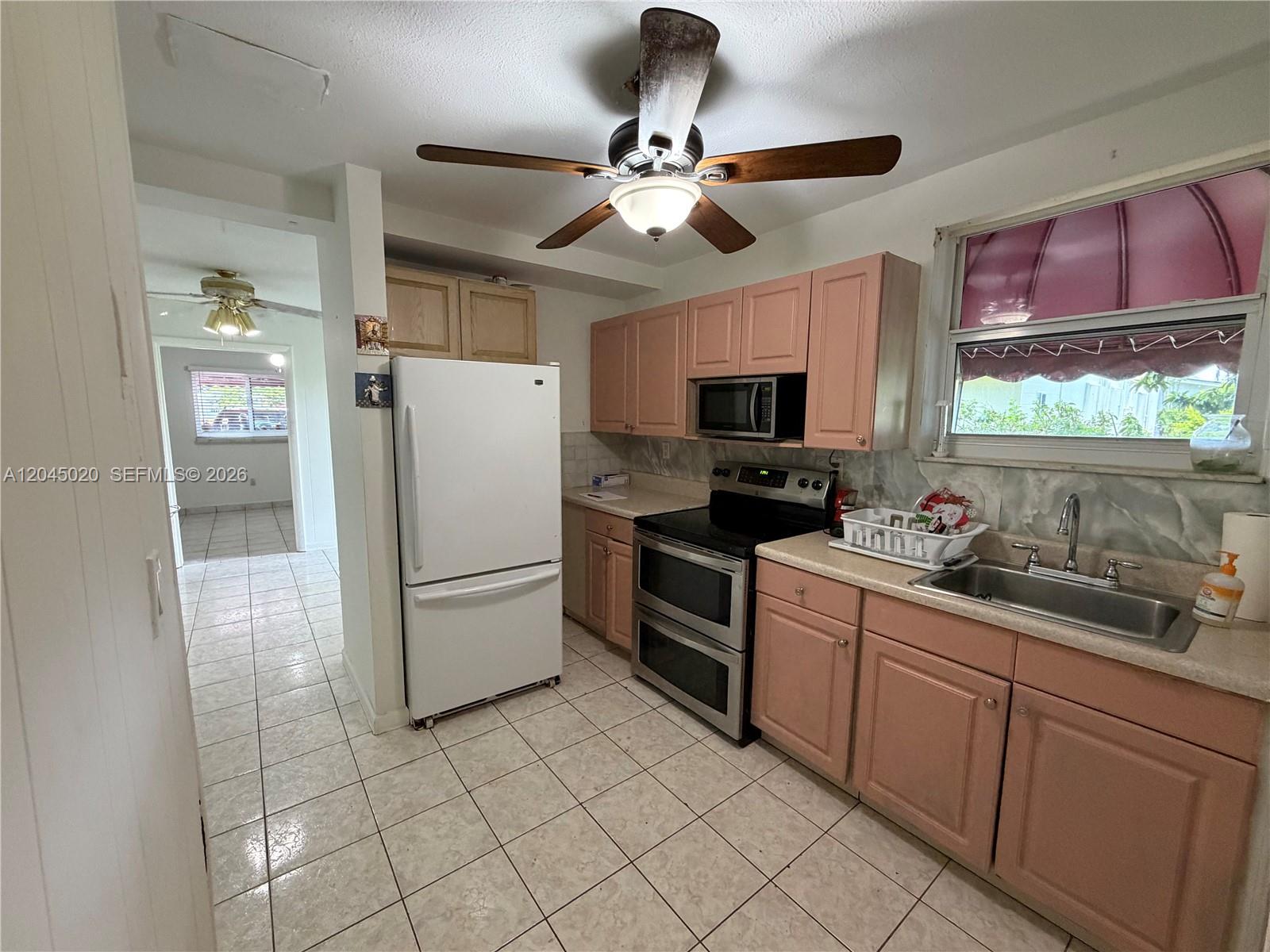 A kitchen features pink cabinets, a white refrigerator, stainless steel appliances, and tiled flooring — 4935 SW 101st Ave # 1, Miami FL 33165, MIAMI, FL