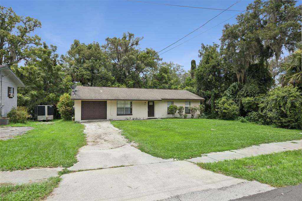 A single-story house with a brown garage door, a concrete driveway, and a large lawn — 397 S ORANGE AVENUE, ORANGE CITY, FL
