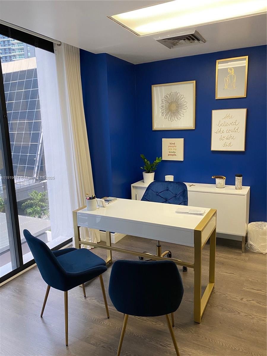 A home office features a white desk, blue velvet chairs, and blue walls with framed art — 1110 Brickell Ave # 313, Miami FL 33131, MIAMI, FL