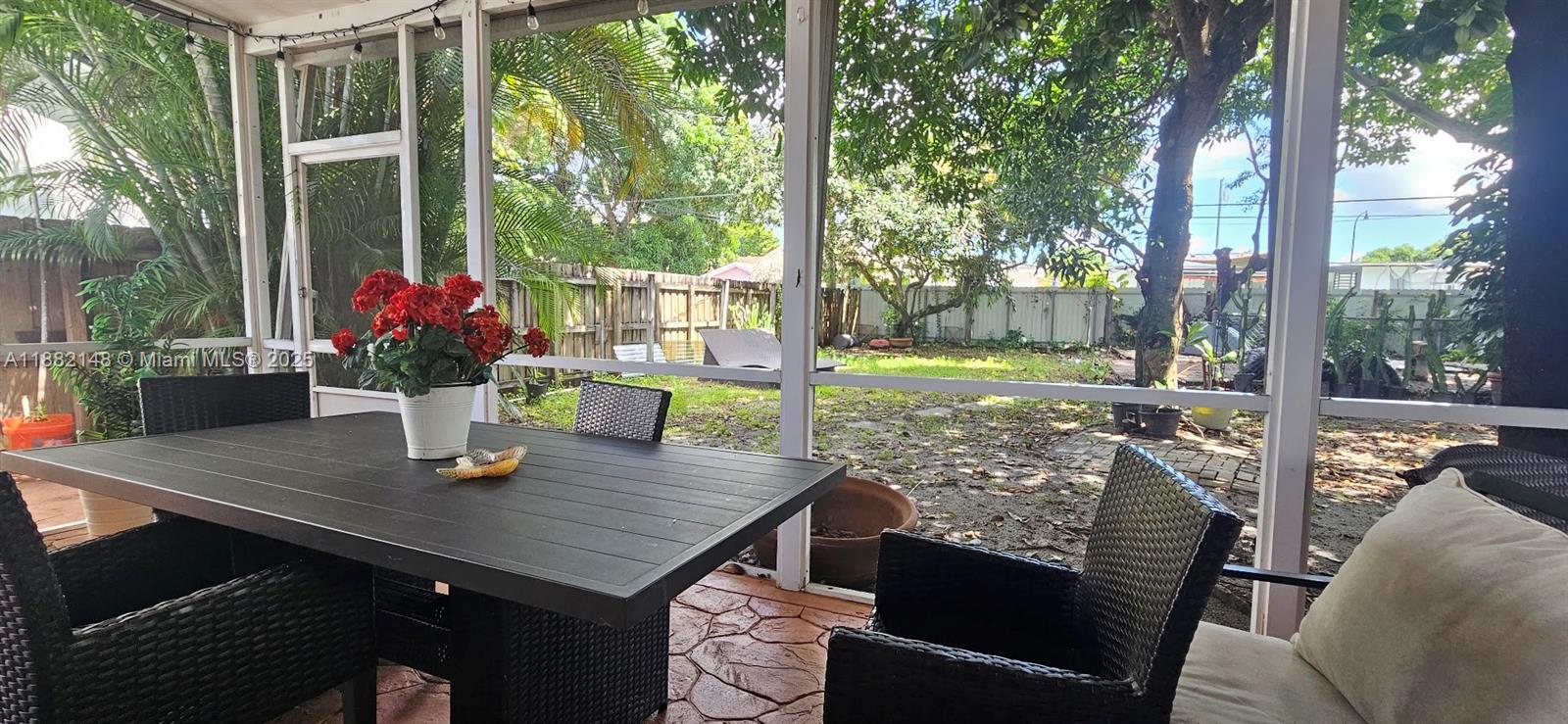 A screened-in patio features a dark dining table, wicker chairs, and a backyard view — 243 NW 62nd Ct, Miami FL 33126, MIAMI, FL