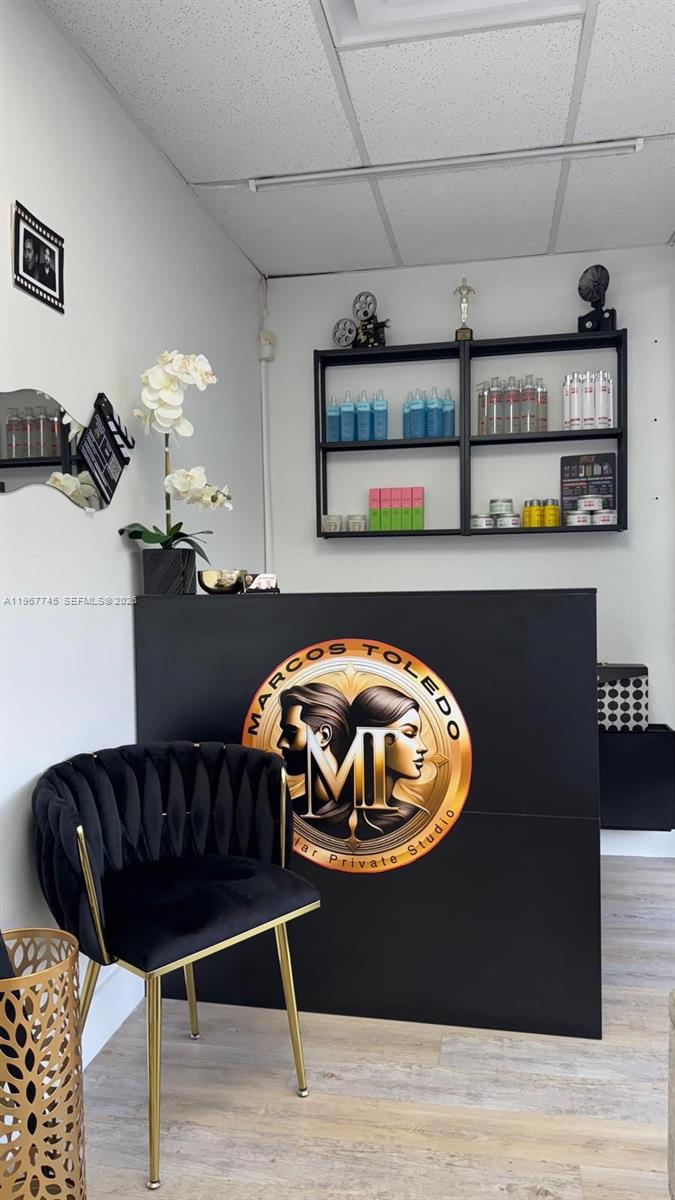 A salon reception area features a black desk with a logo, a black chair, and shelving — 213 Park Blvd, Miami FL 33126, MIAMI, FL