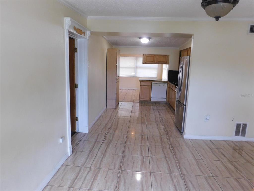 A kitchen with light-colored tile flooring, wooden cabinets, and stainless steel appliances — 4542 BELFAST DRIVE, NEW PORT RICHEY, FL