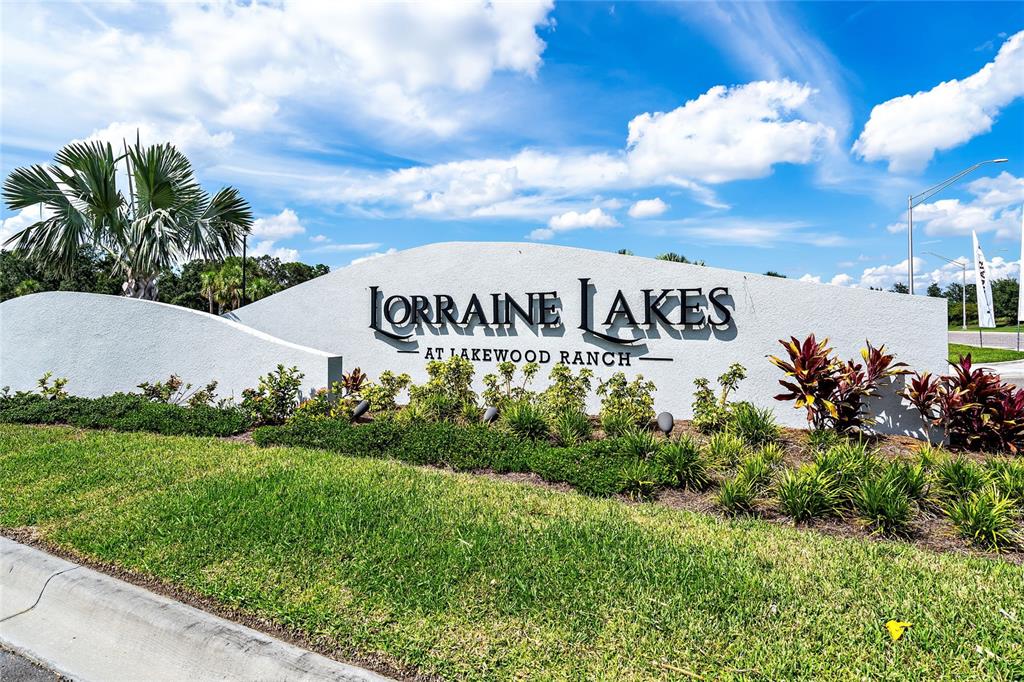 A white monument sign displays the name Lorraine Lakes at Lakewood Ranch against a blue sky — 15004 MISTY WATER CROSSING, LAKEWOOD RANCH, FL
