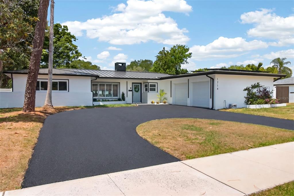 A white single-story house with a black metal roof and a curved asphalt driveway — 1714 INDIAN ROCKS ROAD, BELLEAIR, FL