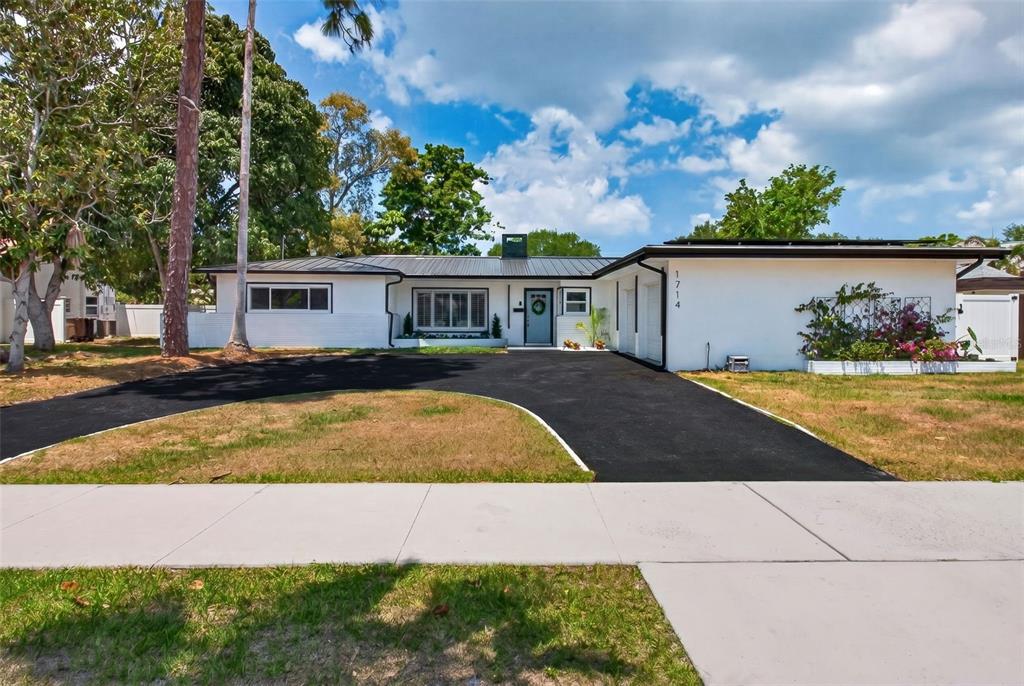 A single-story white house with a black metal roof and a curved asphalt driveway — 1714 INDIAN ROCKS ROAD, BELLEAIR, FL