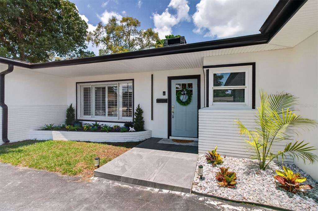 The exterior of a white house features a light blue front door and tiled walkway — 1714 INDIAN ROCKS ROAD, BELLEAIR, FL