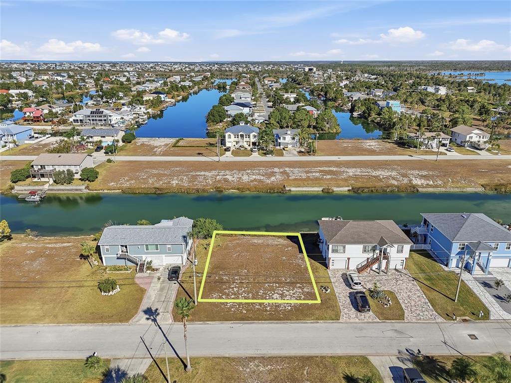 An aerial view shows a vacant waterfront lot outlined in yellow between two existing houses — 4017 BLUEFISH DRIVE, HERNANDO BEACH, FL