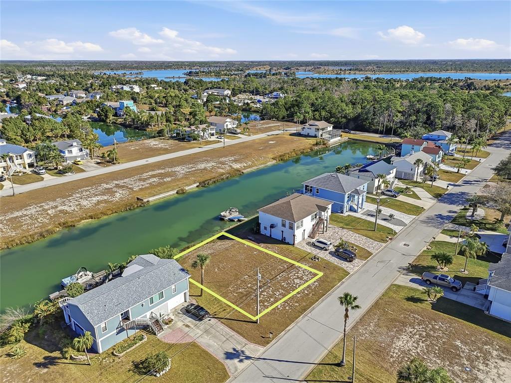 An aerial view shows a vacant waterfront lot situated between two houses along a canal — 4017 BLUEFISH DRIVE, HERNANDO BEACH, FL