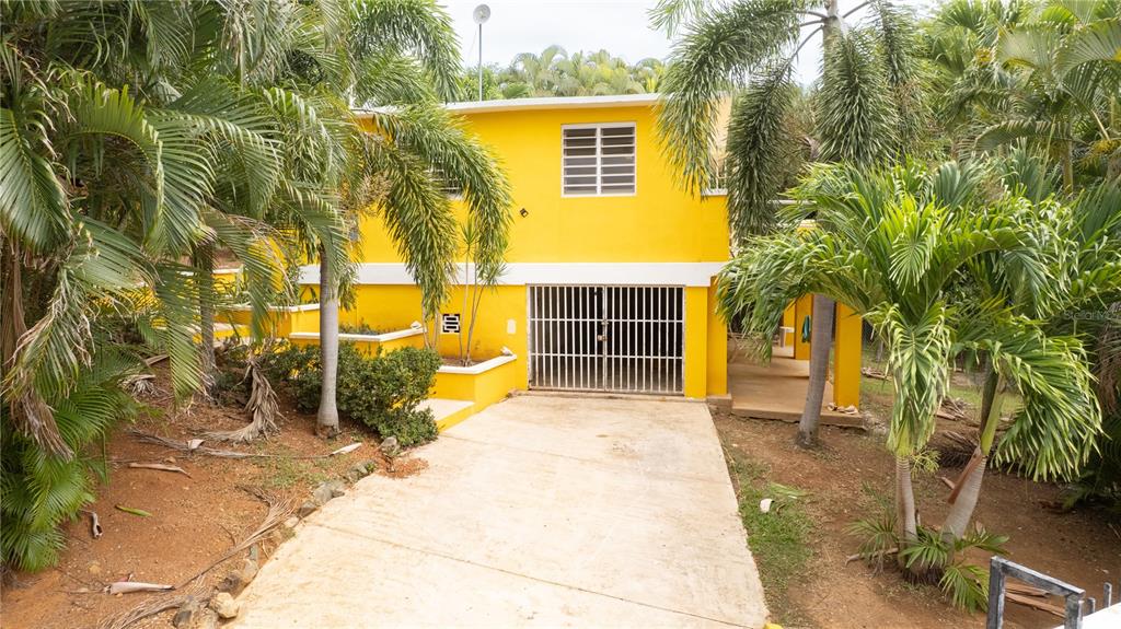 A two-story yellow house with a gated ground-level garage and surrounding palm trees — 615 BRAVOS DE BOSTON, VIEQUES, PR