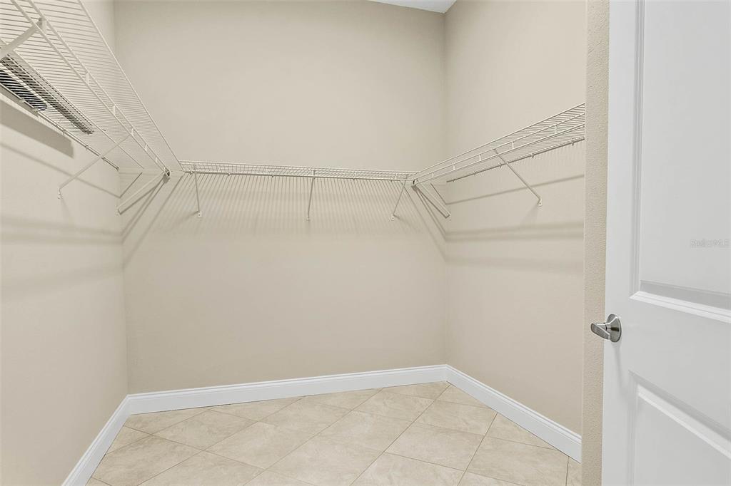 A walk-in closet with white wire shelving, beige walls, and light-colored tile flooring — 3 WHITE HOLLY PLACE, PALM COAST, FL