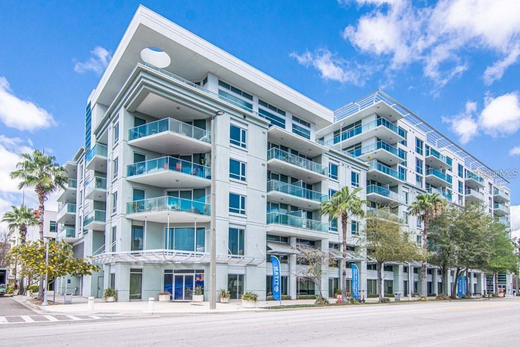 A multi-story modern apartment building with glass balconies and palm trees on a sunny day — 111 N 12TH STREET UNIT 1620, TAMPA, FL